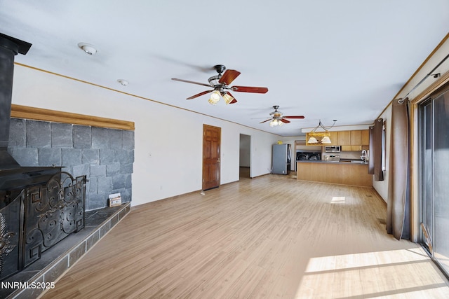 2260 Empire Rd, Reno, NV 89521 - unfurnished living room with a wood stove, ceiling fan, and light wood finished floors