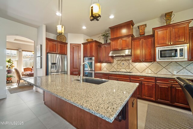 3970 Nature Trl, Reno, NV 89511 - kitchen featuring appliances with stainless steel finishes, under cabinet range hood, arched walkways, light stone countertops, and pendant lighting