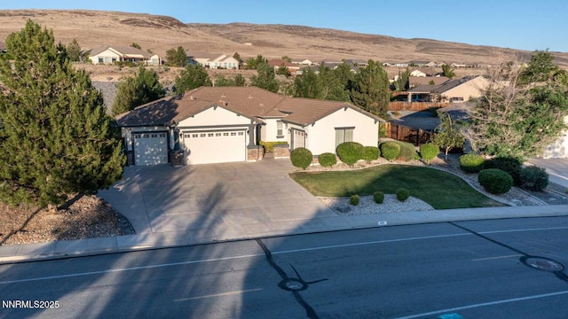 4525 Cobra Dr, Sparks, NV 89436 - ranch-style house featuring a mountain view, a garage, stucco siding, concrete driveway, and a front lawn