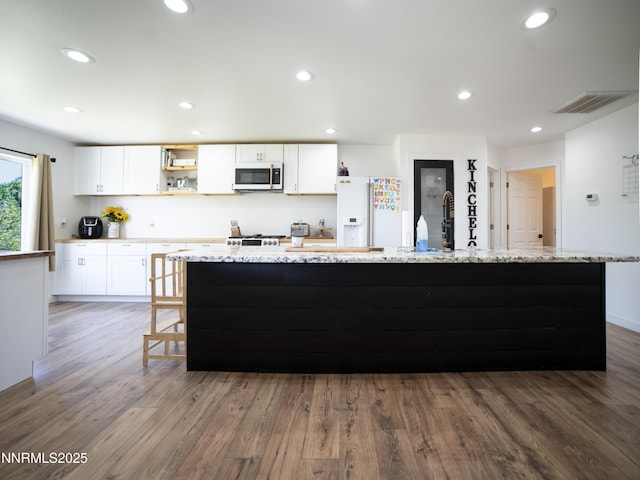5875 Brooke Dr, Winnemucca, NV 89445 - kitchen with white appliances, white cabinets, dark wood-type flooring, a spacious island, and recessed lighting