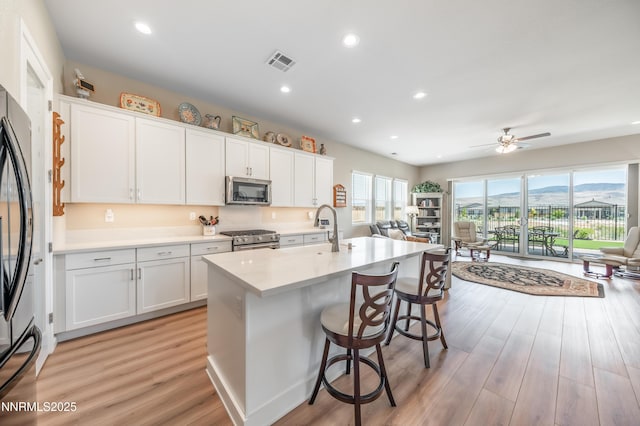 7436 Rustic Towers Dr, Sparks, NV 89441 - kitchen with stainless steel appliances, open floor plan, white cabinetry, a kitchen bar, and recessed lighting