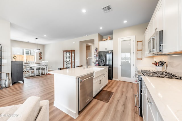 7436 Rustic Towers Dr, Sparks, NV 89441 - kitchen with appliances with stainless steel finishes, white cabinets, light wood-type flooring, an island with sink, and light countertops