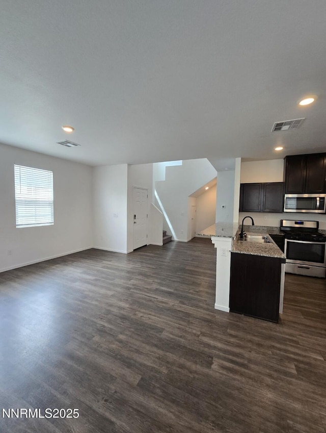 9615 Nautical Mile Rd, Reno, NV 89506 - kitchen featuring stainless steel appliances, open floor plan, recessed lighting, light stone counters, and dark wood-style floors
