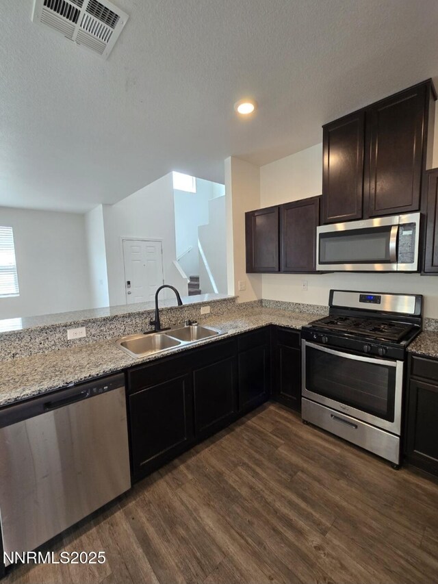 9615 Nautical Mile Rd, Reno, NV 89506 - kitchen with appliances with stainless steel finishes, dark wood finished floors, light stone counters, recessed lighting, and a textured ceiling