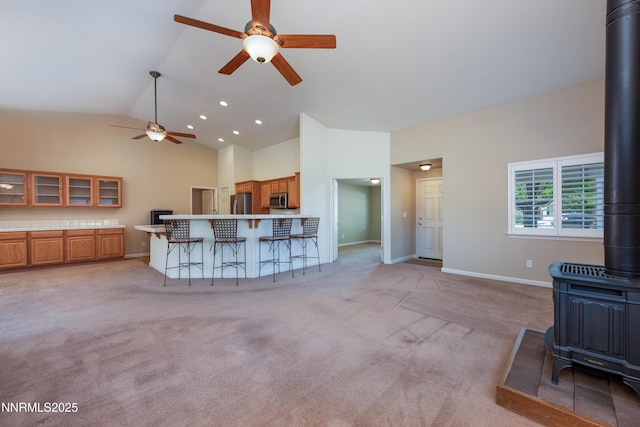 1421 Chiltern Ct, Gardnerville, NV 89410 - living room featuring a wood stove, ceiling fan, high vaulted ceiling, light carpet, and recessed lighting