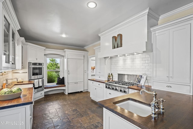 5 Connie Way, Reno, NV 89521 - kitchen with stainless steel double oven, decorative backsplash, white cabinetry, crown molding, and stone tile floors