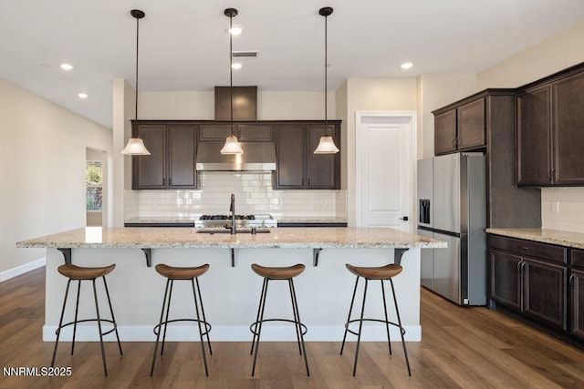 435 Gooseberry Dr, Reno, NV 89523 - kitchen featuring stainless steel refrigerator with ice dispenser, range hood, decorative backsplash, dark brown cabinets, and a center island with sink