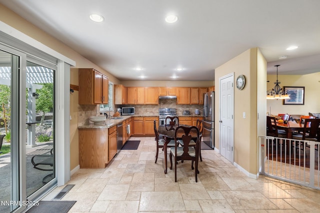 5455 Montego Ct, Reno, NV 89523 - kitchen with stainless steel appliances, stone tile floors, decorative backsplash, recessed lighting, and a chandelier