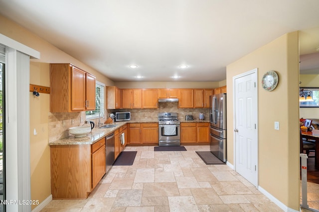 5455 Montego Ct, Reno, NV 89523 - kitchen with appliances with stainless steel finishes, tasteful backsplash, light stone countertops, under cabinet range hood, and light stone finish floors