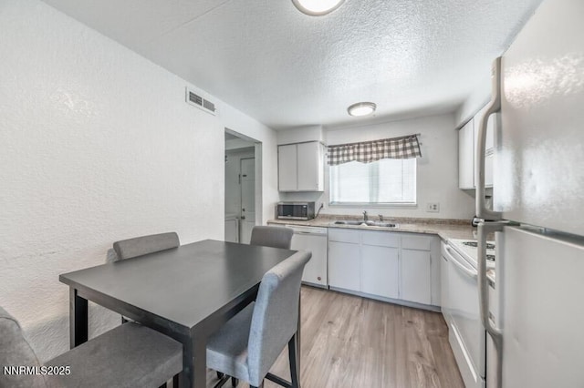 1412 E 9th St Unit 7, Reno, NV 89512 - kitchen featuring white appliances, a textured wall, a textured ceiling, light countertops, and light wood-style flooring