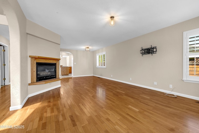 979 University Ridge Dr, Reno, NV 89512 - unfurnished living room featuring arched walkways, light wood-type flooring, and a glass covered fireplace