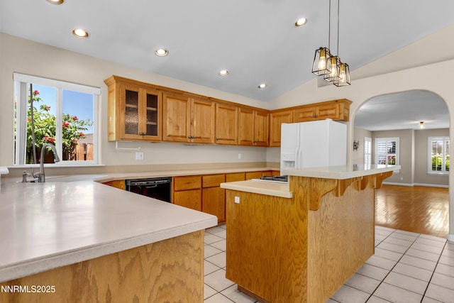 979 University Ridge Dr, Reno, NV 89512 - kitchen with white fridge with ice dispenser, dishwasher, arched walkways, vaulted ceiling, and light countertops