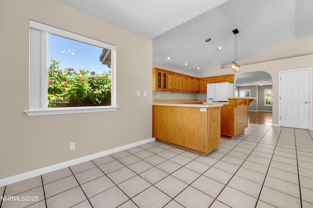 979 University Ridge Dr, Reno, NV 89512 - kitchen with white fridge with ice dispenser, a peninsula, vaulted ceiling, arched walkways, and light countertops