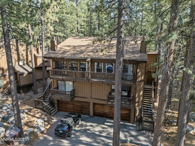 178 Tahoma Cir Unit B, Zephyr Cove, NV 89448 - back of house with stairs, a chimney, an attached garage, and concrete driveway