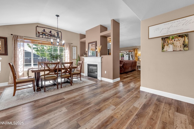 1450 Talon Ct, Spanish Springs, NV 89441 - dining area featuring vaulted ceiling, wood finished floors, plenty of natural light, a chandelier, and a glass covered fireplace