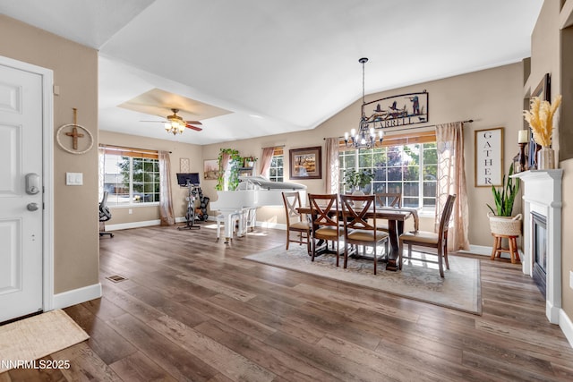 1450 Talon Ct, Spanish Springs, NV 89441 - dining space with dark wood-type flooring, a chandelier, a glass covered fireplace, lofted ceiling, and ceiling fan