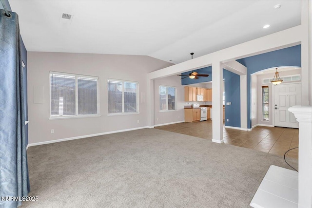158 Desert Springs Ln, Fernley, NV 89408 - unfurnished living room featuring carpet floors, arched walkways, vaulted ceiling, a ceiling fan, and tile patterned floors