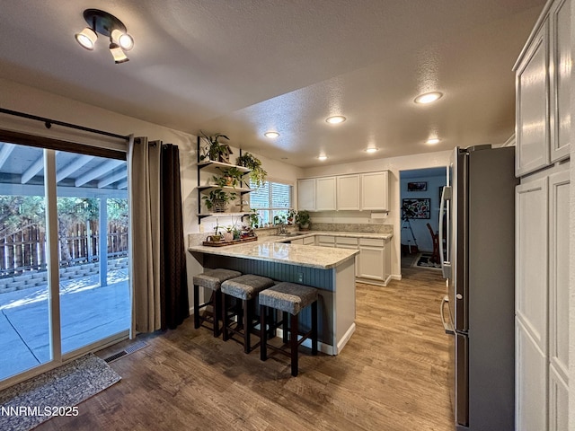 1175 La Cresta Ct, Sparks, NV 89436 - kitchen with freestanding refrigerator, a peninsula, a breakfast bar, light wood-style floors, and white cabinetry