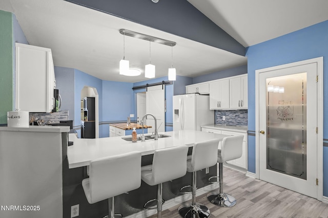 610 Hunter Park Way, Fallon, NV 89406 - kitchen with white fridge with ice dispenser, backsplash, stainless steel microwave, a barn door, and vaulted ceiling