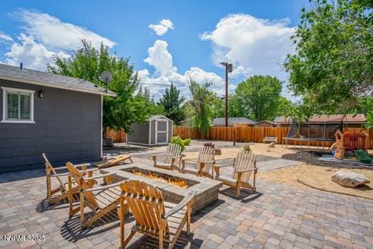1203 Stanford Way, Sparks, NV 89431 - fenced backyard with an outdoor fire pit, a trampoline, a storage shed, and a patio area