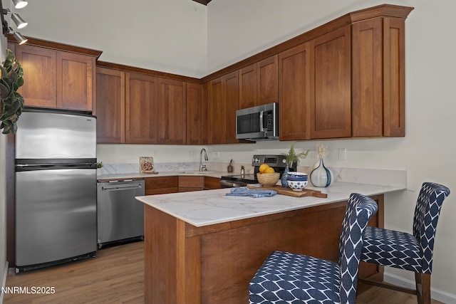 400 Fairview Blvd Unit 20, Incline Village, NV 89451 - kitchen featuring stainless steel appliances, a peninsula, light wood finished floors, brown cabinets, and light stone counters
