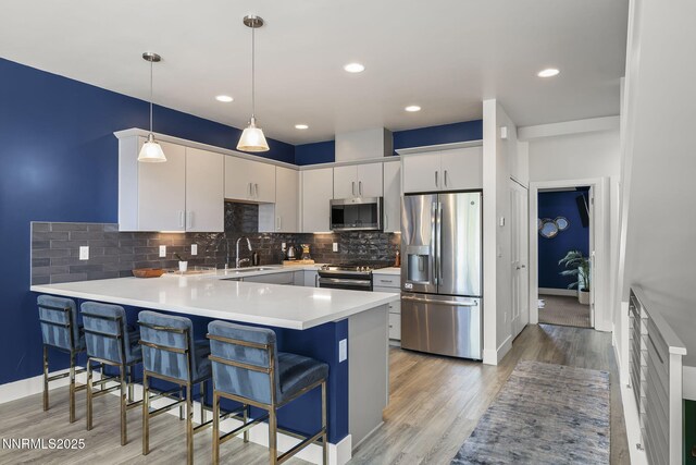 1402 Tonopah St, Reno, NV 89509 - kitchen featuring appliances with stainless steel finishes, a peninsula, decorative backsplash, light countertops, and decorative light fixtures