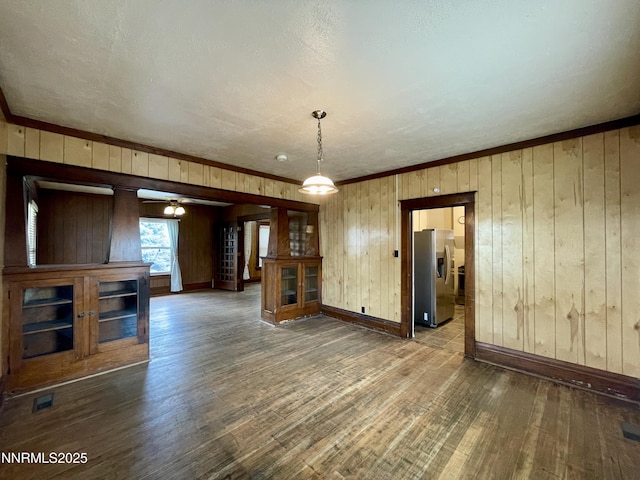 77 Lay St, Winnemucca, NV 89445 - unfurnished living room with dark wood-type flooring, wood walls, ceiling fan, and ornamental molding