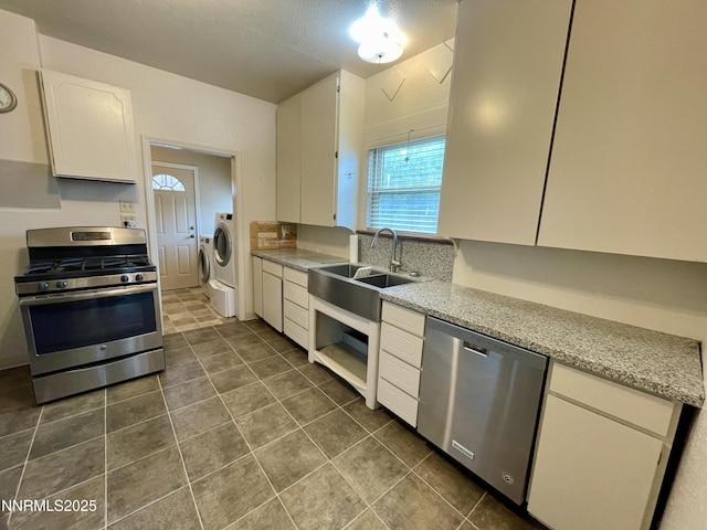 77 Lay St, Winnemucca, NV 89445 - kitchen featuring appliances with stainless steel finishes, white cabinetry, dark tile patterned floors, and washer / dryer