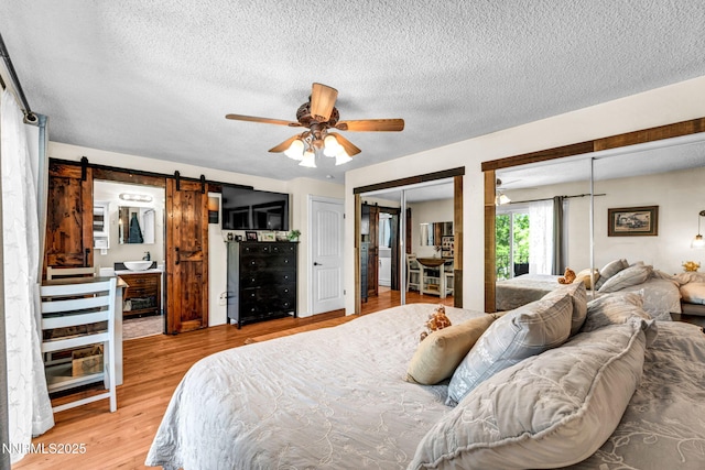 700 Highland St, Carson City, NV 89703 - bedroom with a barn door, multiple closets, a textured ceiling, light wood-style floors, and ceiling fan