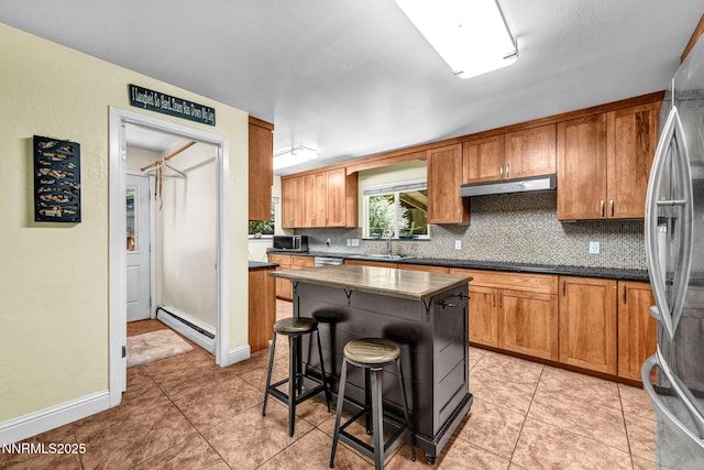 700 Highland St, Carson City, NV 89703 - kitchen featuring appliances with stainless steel finishes, backsplash, a baseboard heating unit, and a breakfast bar