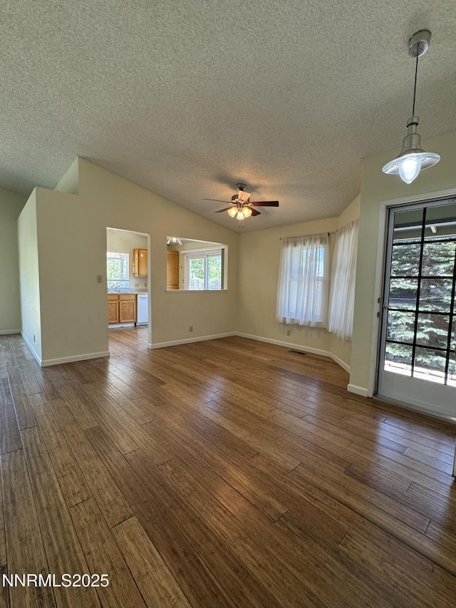 6559 Fall River Cir, Reno, NV 89523 - unfurnished living room featuring a textured ceiling, lofted ceiling, ceiling fan, and dark wood finished floors