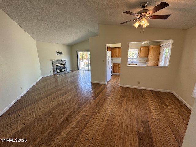 6559 Fall River Cir, Reno, NV 89523 - unfurnished living room featuring vaulted ceiling, a textured ceiling, dark wood-style flooring, a fireplace, and ceiling fan