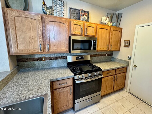 4066 Snowshoe Ln, Reno, NV 89502 - kitchen with appliances with stainless steel finishes, light countertops, light tile patterned floors, and brown cabinetry