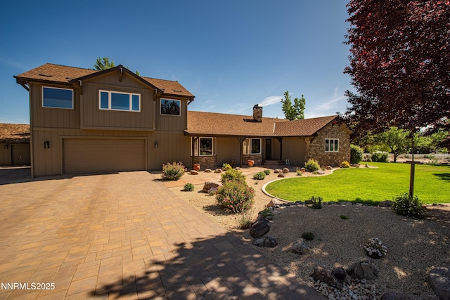 15045 Heathcliff Dr, Reno, NV 89511 - view of front of home with an attached garage, a chimney, a front lawn, decorative driveway, and stone siding