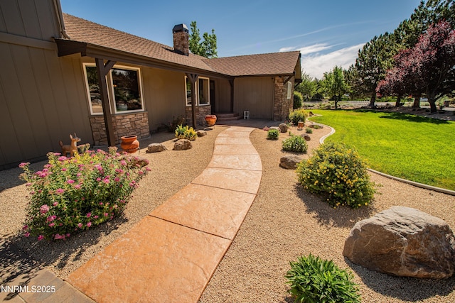 15045 Heathcliff Dr, Reno, NV 89511 - view of exterior entry featuring a chimney, stone siding, a lawn, and a shingled roof