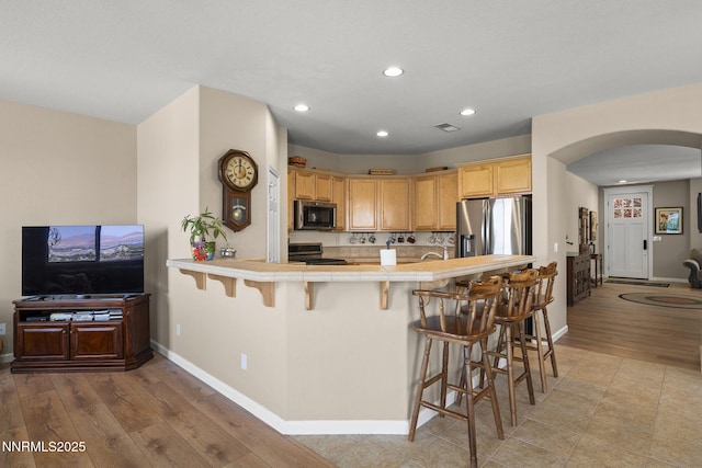 3226 Banestone Rd, Sparks, NV 89436 - kitchen featuring stainless steel appliances, arched walkways, recessed lighting, light wood-type flooring, and a breakfast bar area