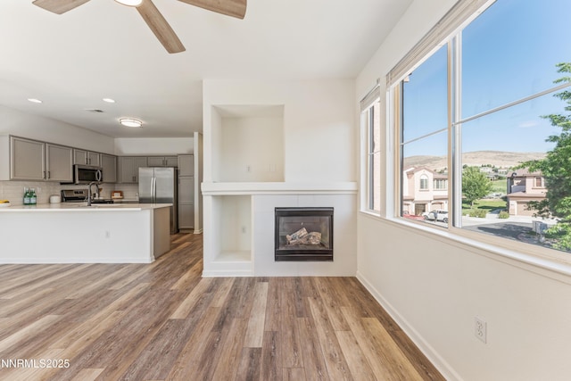 6120 Ingleston Dr Unit 621, Sparks, NV 89436 - unfurnished living room featuring light wood-type flooring, a tiled fireplace, a ceiling fan, and recessed lighting