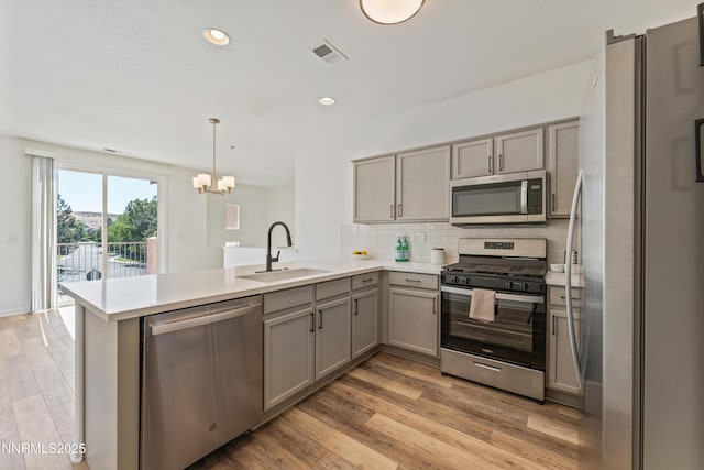 6120 Ingleston Dr Unit 621, Sparks, NV 89436 - kitchen featuring stainless steel appliances, a peninsula, gray cabinetry, a chandelier, and decorative backsplash