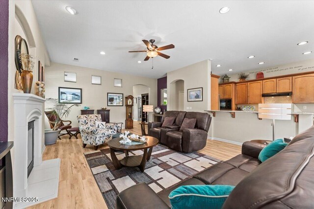 6648 Equation Dr, Sparks, NV 89436 - living room featuring arched walkways, ceiling fan, light wood-type flooring, recessed lighting, and a fireplace with raised hearth