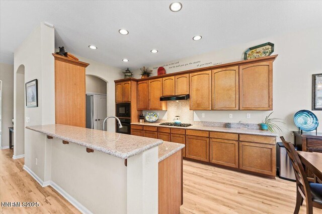 6648 Equation Dr, Sparks, NV 89436 - kitchen featuring black appliances, arched walkways, under cabinet range hood, a peninsula, and recessed lighting
