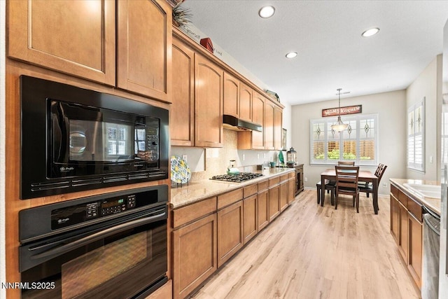 6648 Equation Dr, Sparks, NV 89436 - kitchen with black appliances, light wood-style floors, under cabinet range hood, brown cabinets, and decorative light fixtures