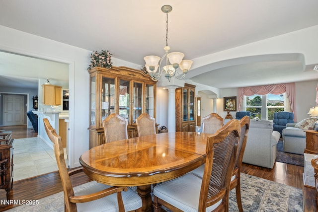 3555 Vista Blvd, Sparks, NV 89436 - dining area with arched walkways, a chandelier, decorative columns, and dark wood finished floors