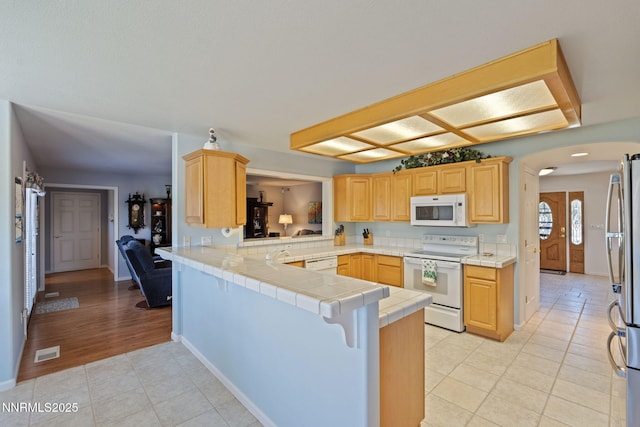 3555 Vista Blvd, Sparks, NV 89436 - kitchen with white appliances, a peninsula, arched walkways, light tile patterned floors, and tile counters