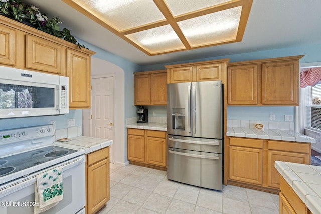 3555 Vista Blvd, Sparks, NV 89436 - kitchen with white appliances, tile counters, arched walkways, and light tile patterned floors