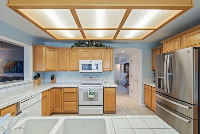 3555 Vista Blvd, Sparks, NV 89436 - kitchen with white appliances, arched walkways, tile countertops, and light tile patterned floors