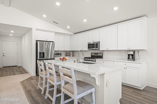 6496 Arc Dome Dr, Carson City, NV 89701 - kitchen featuring stainless steel appliances, vaulted ceiling, wood finished floors, recessed lighting, and a breakfast bar