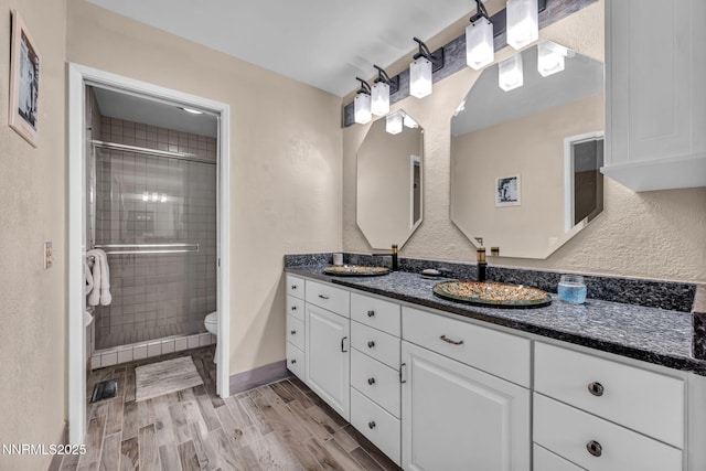 6437 Meadow Valley Ln, Reno, NV 89519 - full bathroom with double vanity, wood finished floors, a shower stall, and a textured wall