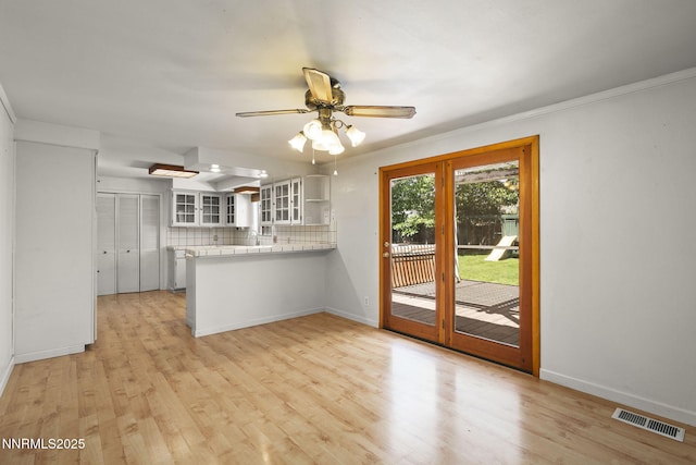 9100 Rain Dance Way, Reno, NV 89506 - kitchen featuring a peninsula, glass insert cabinets, light wood-style floors, and tasteful backsplash