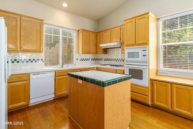6993 Cinnamon Dr, Sparks, NV 89436 - kitchen featuring white appliances, tile counters, under cabinet range hood, light wood-type flooring, and backsplash