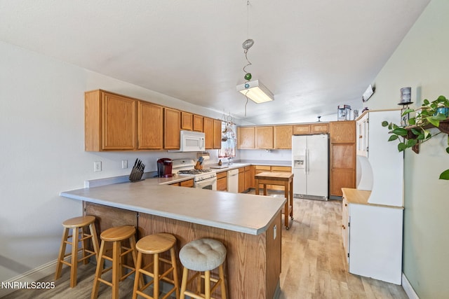 5886 Wishbone Ct, Sun Valley, NV 89433 - kitchen featuring white appliances, a peninsula, light countertops, light wood-style flooring, and a breakfast bar